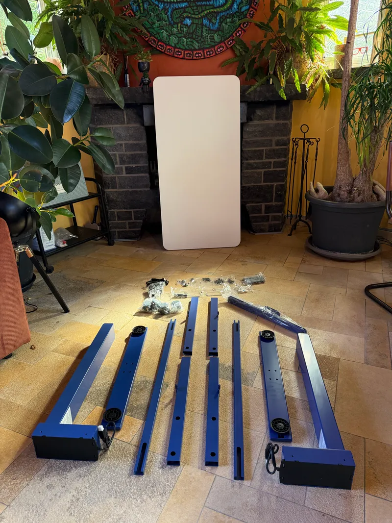 Pièces du cadre Maidesite T2 étalées au sol avant montage, plateau appuyé contre la cheminée